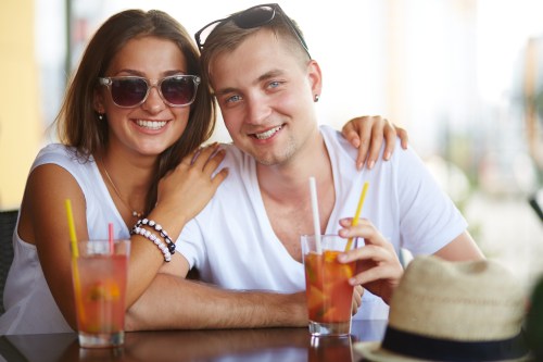 Young couple sitting in cafe on summer day and looking at camera